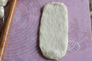 取一个面团擀成椭圆形，拍去面团两侧气泡。