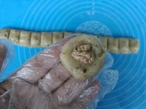 取一个小剂子揉圆，用大拇指按扁，中间放一颗核桃仁。