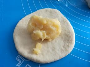 取一个小面团，擀面杖擀成圆片，放上适量自制的奶黄酱（自制奶黄馅的方法看我上一篇食谱），