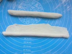 取一个小面团，擀成长圆片，底部压薄，自下而上卷起。