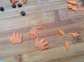 胡萝卜切薄片，用小刀刻出小鸡的嘴巴和头冠。