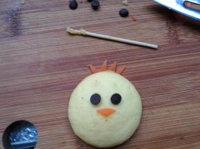 眼睛用耐烤巧克力豆豆装饰，可以沾一点红胡萝卜切薄片，用小刀刻出小鸡的嘴巴和头冠。薯泥固定在蛋黄饼干上。组装在一起，一个可爱的小鸡就做好了。