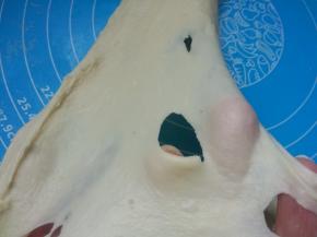 取出面团，置硅胶垫上，手揉至扩展阶段（面团用手掌根部推出去，然后再拉回来）。能够撑开粗膜，用手指戳个洞，边缘呈锯齿状。