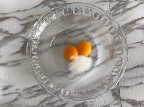 先来制作卡仕达酱。
蛋黄中加入细砂糖，用手动打蛋器搅打均匀。