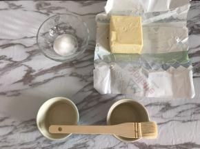 首先对模具进行防粘处理，这一步非常重要，处理好模具，舒芙蕾在烘烤的过程中才能垂直攀升。
黄油室温软化，用毛刷蘸取黄油刷满舒芙蕾碗内侧，刷好后倒入细砂糖，在碗内转一圈，让四周都粘满糖后，把碗在桌子上磕一下，倒出多余的糖。
多余的糖可以用于制作卡仕达酱，但不要用于打发蛋清。