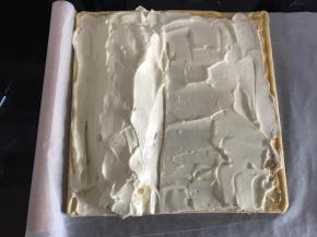 淡奶油抹在蛋糕片上。因为做e型卷，所以左手边将淡奶油堆成小山丘，用擀面杖和油纸辅助，将蛋糕卷卷起。