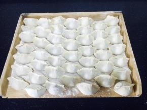 饺子屉上撒少许面粉，把逐个包好的饺子摆放好。
撒面粉是防止饺子粘在屉上。