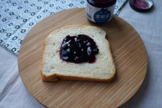 取一片面包，在中间抹上蓝莓酱