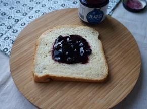取一片面包，在中间抹上蓝莓酱