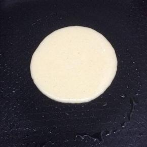 平㡳锅倒入少许的油，等温热后，用勺子舀一勺面糊倒入平底锅中，高一点倒比较圆