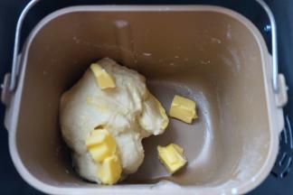 将面包桶安放在面包机中，选择一个和面程序，10分钟；面团略有光滑后，加入软化的黄油，再来一个和面程序，这次设定20分钟