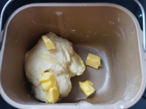 将面包桶安放在面包机中，选择一个和面程序，10分钟；面团略有光滑后，加入软化的黄油，再来一个和面程序，这次设定20分钟