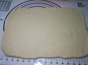 面团从桶中取出，放在揉面垫上，排气揉圆，盖保鲜膜松弛10分钟，然后擀成长40厘米、宽30厘米左右的长方形面片，厚约6、7毫米