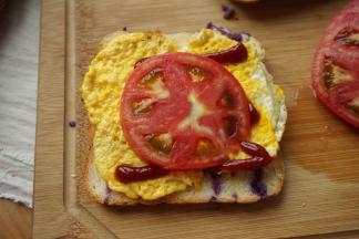 做个简单的三明治吧：面包片，番茄酱、煎蛋、西红柿片准备好，也可以根据口味调整用料；取一片面包，铺一层鸡蛋、挤一点番茄酱、放一大片西红柿