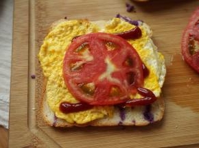做个简单的三明治吧：面包片，番茄酱、煎蛋、西红柿片准备好，也可以根据口味调整用料；取一片面包，铺一层鸡蛋、挤一点番茄酱、放一大片西红柿