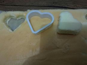 晾至手温后，用一张干净的油纸放在蛋糕上，翻过来，揭开油布，用揭开的油布盖在蛋糕上，再翻过来。用心形饼干模具压出形状。