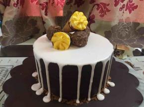 蛋糕胚下面用可可百利薄脆片装饰四周，棉花糖淋面均匀地淋在蛋糕胚，制造出滴落的效果