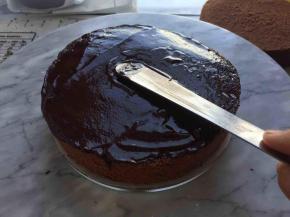 将一片蛋糕片放在辅了油纸的PVC圆片上，抹上巧克力甘那许