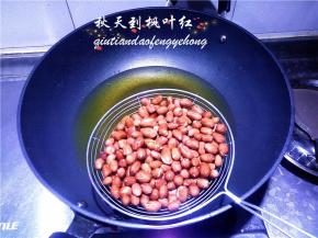 把油锅里的油炸花生捞出控净油。