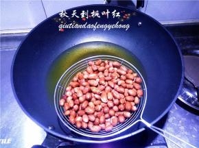 把油锅里的油炸花生捞出控净油。