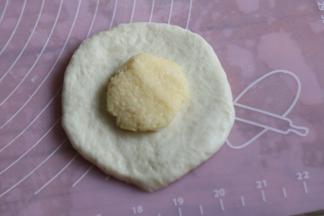 取一个面团，按扁擀开，包入椰蓉馅。