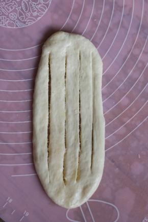 把包好面团轻柔地擀成长椭圆形，用切面刀纵向切四刀注意两头不要切断。