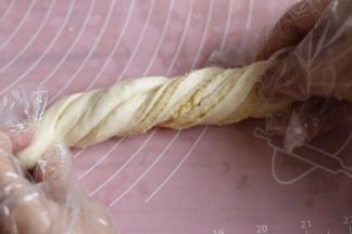 提起面团两头，慢慢拉长点，两条长边同时向中间卷起，两头向扭麻花一样扭二至三圈。