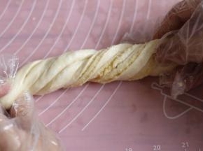 提起面团两头，慢慢拉长点，两条长边同时向中间卷起，两头向扭麻花一样扭二至三圈。