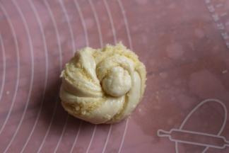 两头向中间盘起，打个结，再把接头一头掏从面团出来，另一头压底。