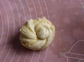 两头向中间盘起，打个结，再把接头一头掏从面团出来，另一头压底。