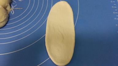 取松驰好的面团，擀成椭圆形。