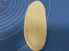 取松驰好的面团，擀成椭圆形。