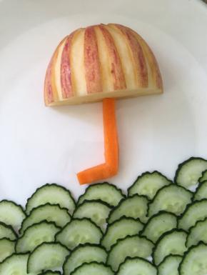 把苹果和胡萝卜摆放在盘中，形成一把雨伞