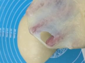 8. 适时地检查面筋的强度，把面团小心的伸开，这时候面团已经可以形成一层薄薄的薄膜，但是薄膜并不是特别坚韧，还是比较容易破裂，破裂的洞口呈不规则的形状，而不是光滑的圆形，这个时候面团就达到了扩展阶段，这个时候做餐包是可以的了