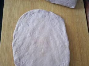 把面团平均分成2份，取一份用擀面杖轻轻的擀成接近长方形的面片（不要用力排气）。