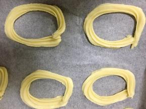 将裱花袋里的材料挤在铺有油纸的烤盘上，成椭圆形，尽量挤的一样大小