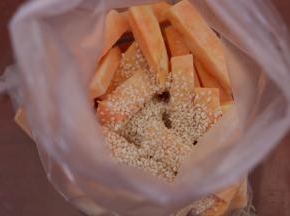 2.放入塑料袋里倒入植物油和白芝麻混合均匀