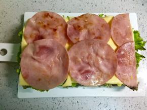 铺上火腿片，其中一片要切成两半。