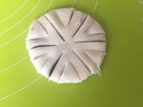 反过来压到1cm厚的圆饼，先用刀轻轻划分为6份，再顺着印子切下（注意不要切断，中间要留着不切），再在每一份中间切两刀较短的口，如上图