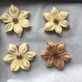 放入铺了油纸的烤盘中，花芯中间沾一点蛋黄液，撒上黑芝麻，烤箱预热180度，上下热风循环火，烤25分钟