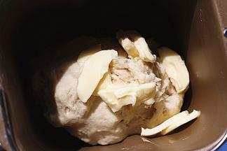 启动面包机揉面功能，揉到面团光滑后，加入黄油继续揉（夏天黄油无需软化，面包机会散热，开着盖子揉面团即可）