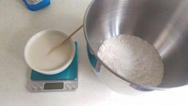 把静止好的酵母水倒入已经称好面粉中。我用厨师机揉，低速揉到表面光滑。如果用手揉也是一样的，揉到3光（盆光，手光，面团光）就可以咯。