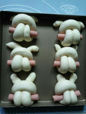 全部做好放到金盘里，顺便整理一下耳朵，然后把两边的香肠稍微剪去一些。盖保鲜膜发酵2倍大，现在我这边室温35°左右，就不放烤箱里发酵了。