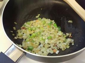 在加入葱头。炒出香味。再加入腊肠，也是炒出香味。