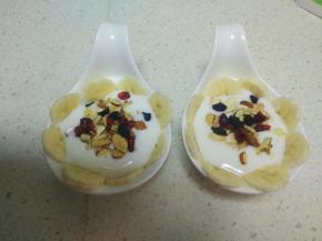 把香蕉片放在酸奶的周围，把干果围成一个小圈。