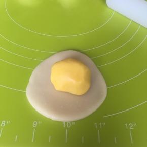 取一个水油皮压扁擀圆，包入一个油酥