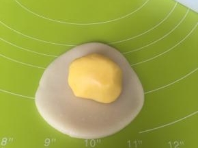 取一个水油皮压扁擀圆，包入一个油酥