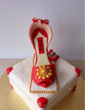 将做好的鞋子轻轻放在蛋糕胚上，按压固定，随意沾些金色糖珠装饰