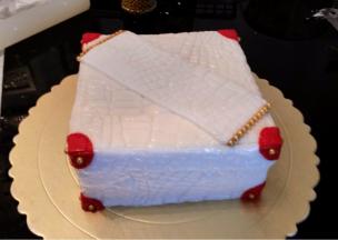 白色翻糖膏擀平，擀薄，后鳄鱼纹模印出纹理，轻轻包住蛋糕胚，抹平。红色干佩斯做好皮鞋盒的点缀