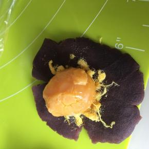 取红豆沙包入肉送和一个烤好的咸鸭蛋黄，全部包好滚圆
